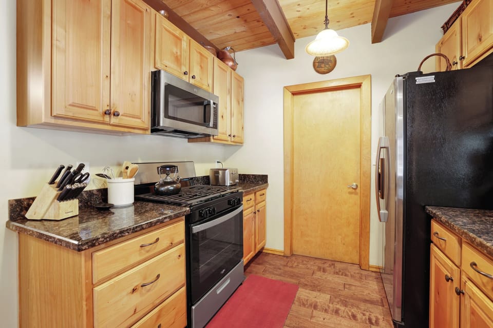Fully equipped cabin kitchen with wood cabinets, stove, fridge, microwave, and coffee maker—perfect for cooking meals, morning coffee, and feeling right at home on your stay.