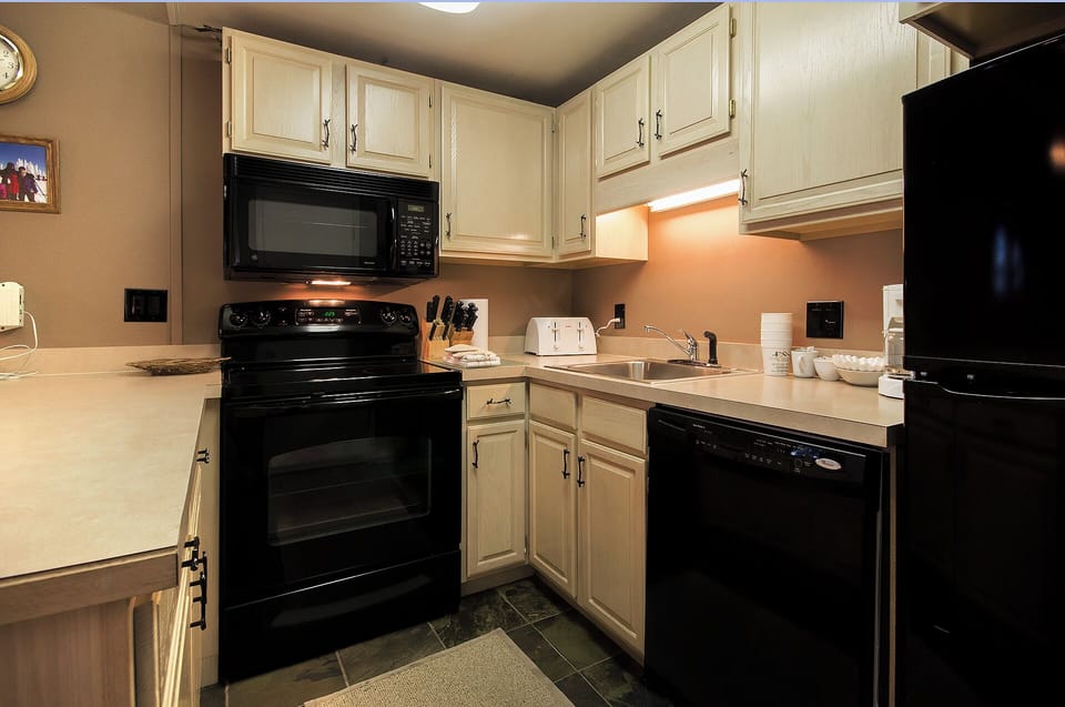 Your fully equipped kitchen features cream cabinets, black appliances, and everything you need to prepare meals during your stay.
