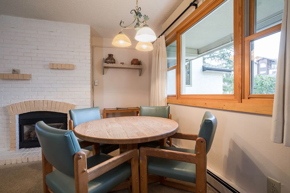 Gather around your cozy dining nook, where warm wood meets soft leather seating beside a charming brick fireplace.