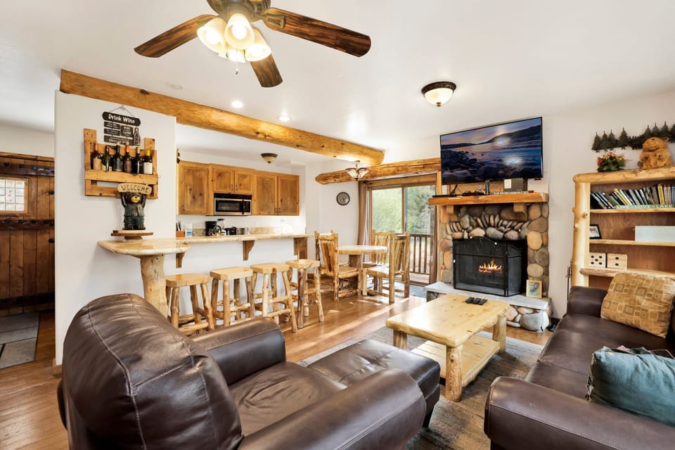 This open-concept living area features a stone fireplace, leather seating, and a charming breakfast bar.