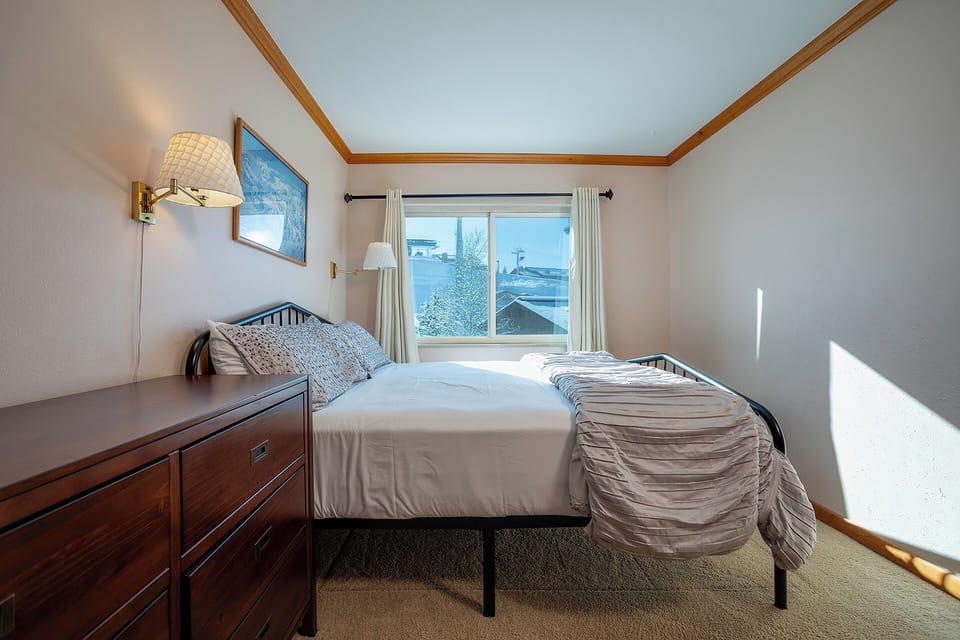 Wake up to gentle morning light streaming through your window in this cozy bedroom with crisp white linens and charming wood accents.
