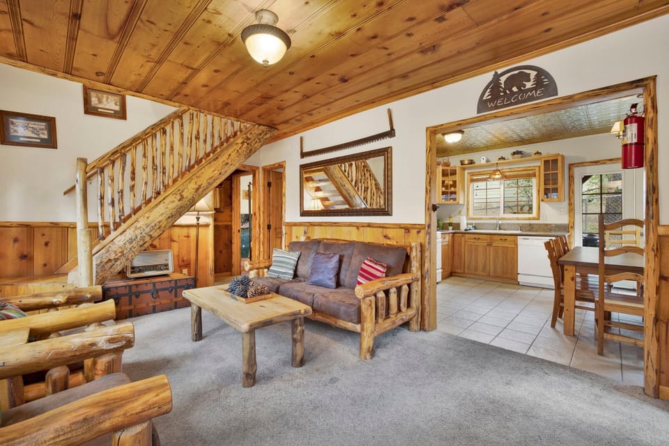 Cozy mountain living room with a stone fireplace, comfy seating, and smart TV—perfect for relaxing evenings, movie nights, and warm cabin vibes after outdoor adventures.