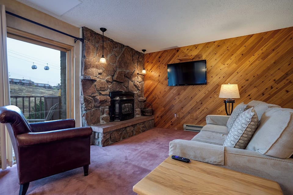Cozy up in your alpine living room with a crackling stone fireplace, warm wood walls, and mountain views from your window.