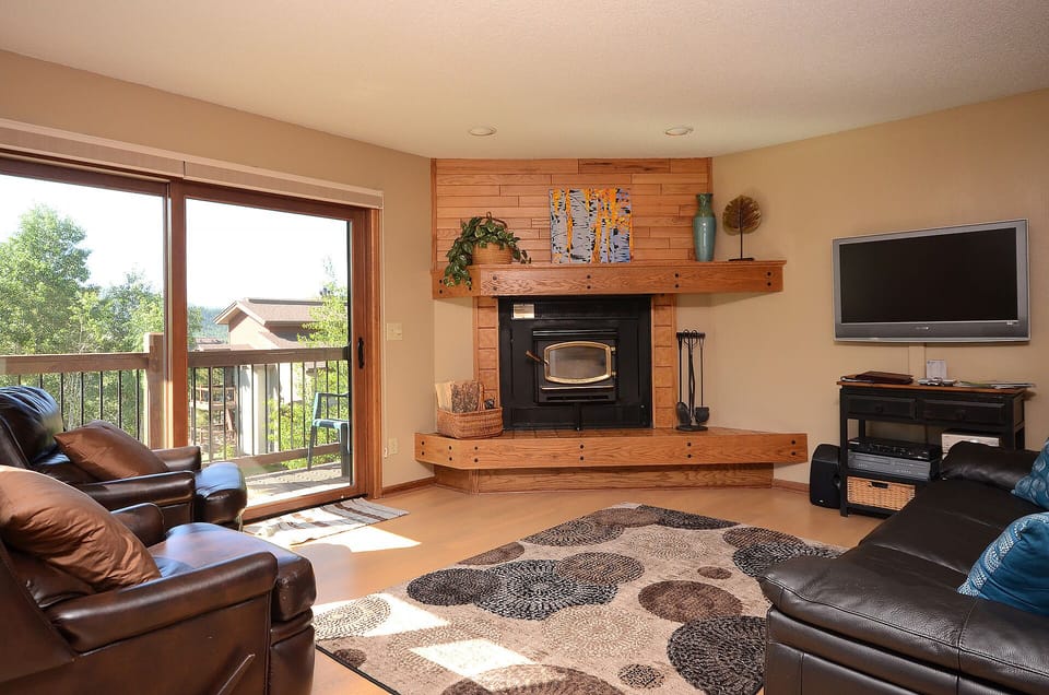 Unwind in your cozy living room where leather seating surrounds a warm fireplace, perfect for relaxing after mountain adventures.