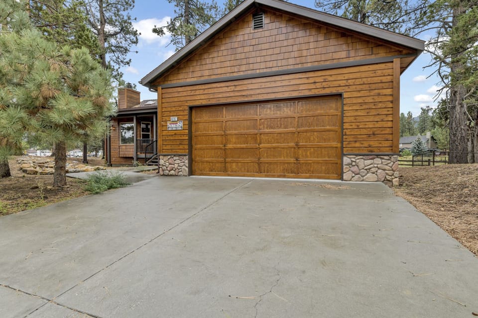 Welcoming cabin entry surrounded by towering pine trees, offering fresh mountain air and a peaceful forest setting—the perfect first impression for your Big Bear Lake getaway.