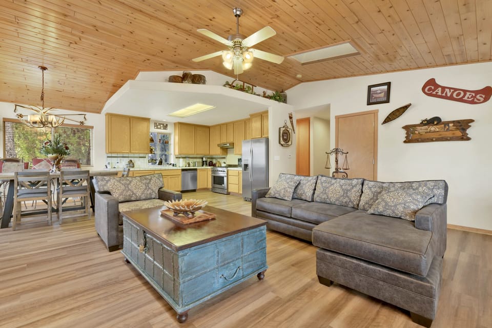 Cozy mountain living room with wood ceilings, stone fireplace, comfy seating, and smart TV—perfect for relaxing evenings, movie nights, and warm cabin vibes after outdoor adventures.