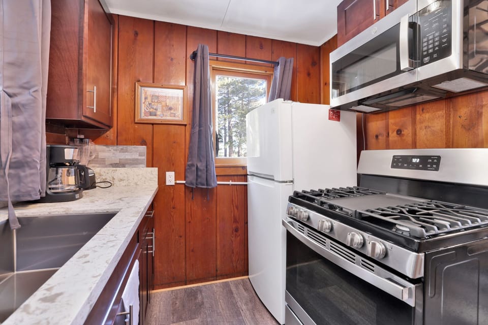 Kitchen with a refrigerator, stove, microwave, oven,  coffee machine, and a blender.