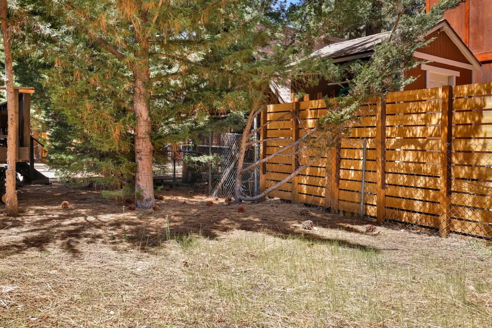 This cozy outdoor space is bordered by a rustic wooden fence and tall, mature trees, offering an extra layer of privacy and shade. The natural landscape provides a peaceful buffer, making it a quiet spot to enjoy the mountain air.
