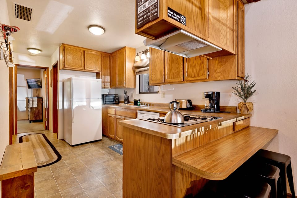 Fully equipped cabin kitchen with warm wood cabinets,stove, fridge, microwave, and coffee maker—perfect for cooking meals, morning coffee, and feeling right at home on your Airbnb stay.