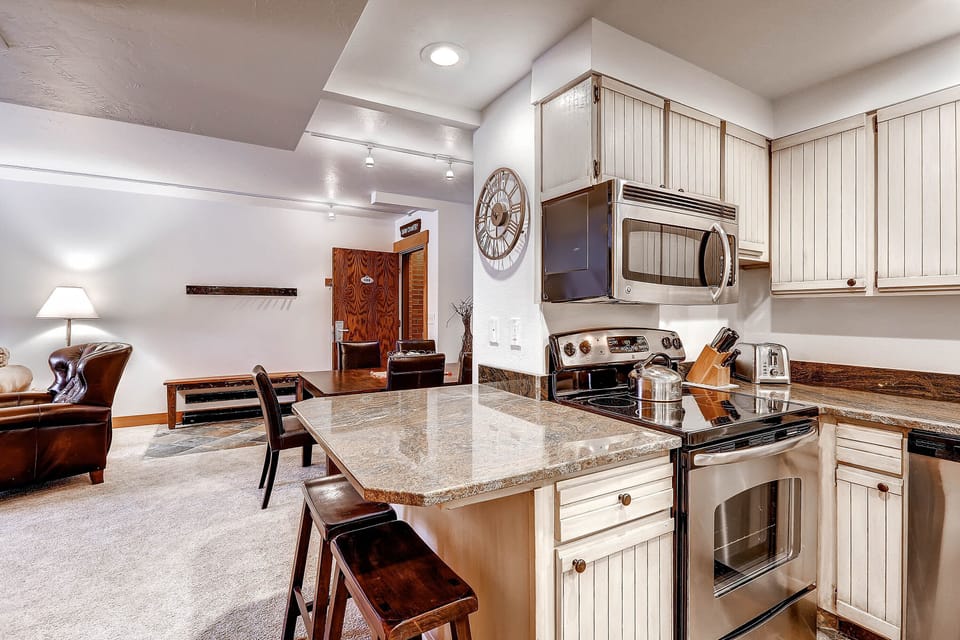 Park Station 134's kitchen with breakfast bar with seating for two, granite counters, and stainless steel microwave and oven.