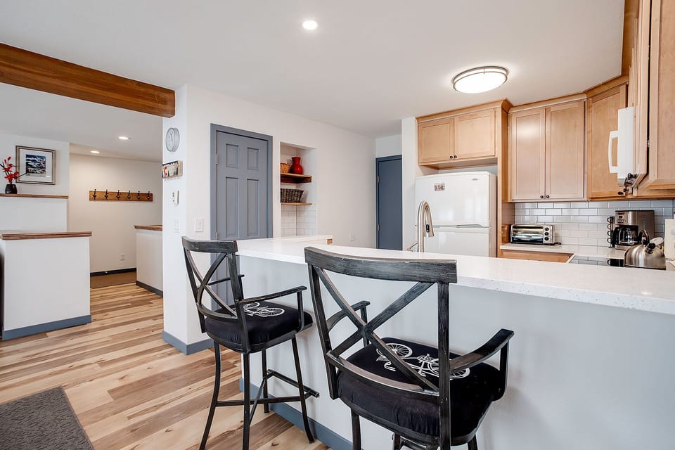 Your modern kitchen features warm wood cabinetry, white countertops, and a breakfast bar where you can enjoy morning coffee together.