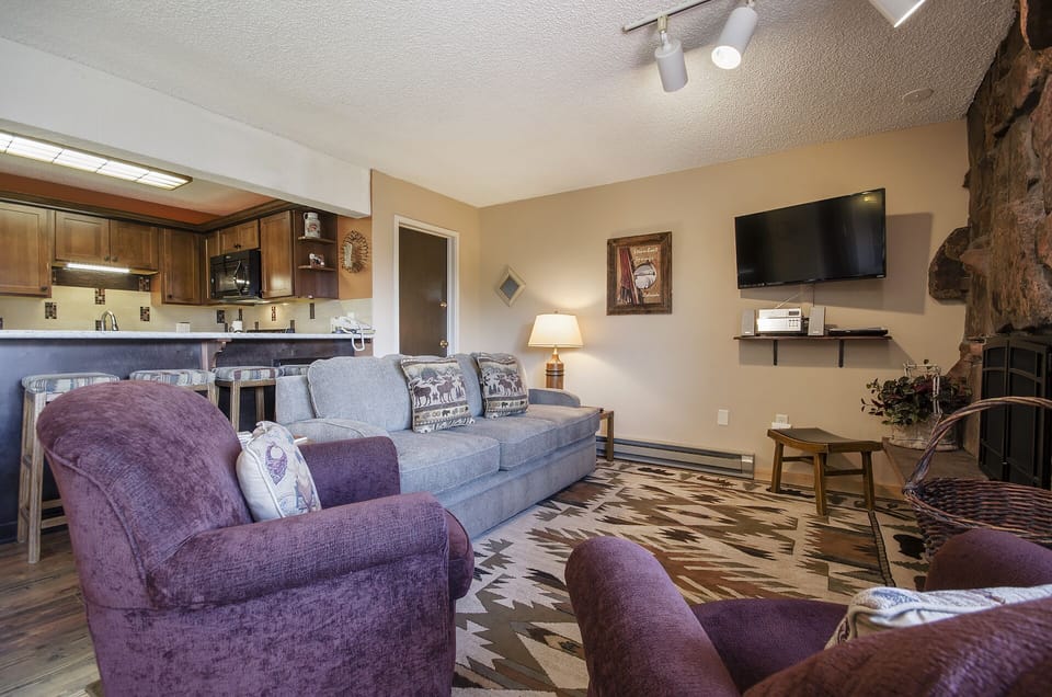 Unwind in your cozy living room with plush seating, a stone fireplace, and mountain-themed décor creating the perfect retreat atmosphere.