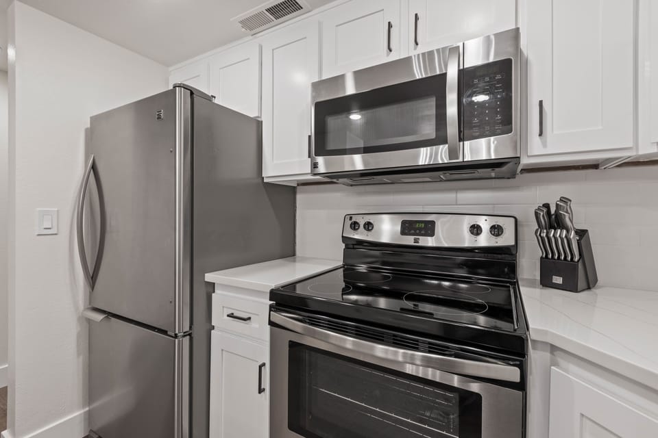 The kitchen has stainless steel appliances and white cabinets.