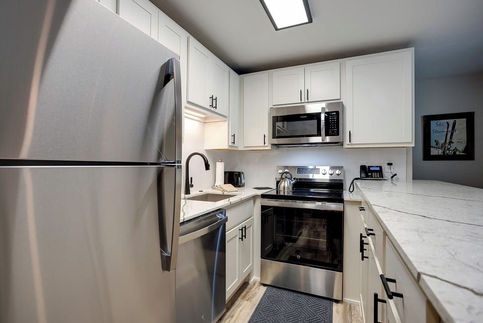Cook your favorite meals in this bright, fully-equipped kitchen with stainless steel appliances and marble countertops.