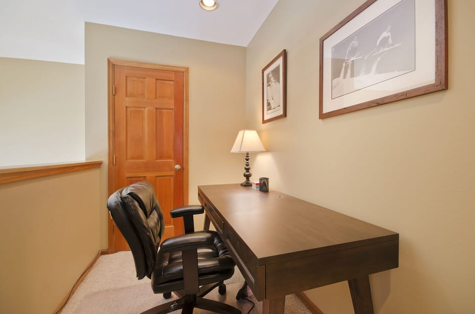 Your private workspace awaits with a spacious desk, comfortable leather chair, and warm lighting for productive hours.
