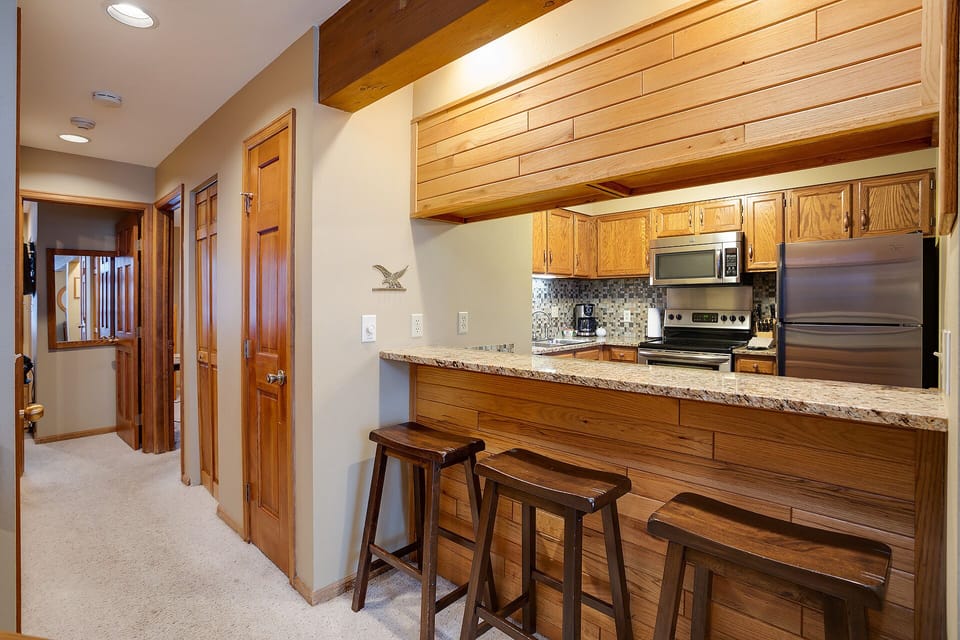Your fully equipped kitchen features beautiful wood cabinetry, granite counters, and a convenient breakfast bar perfect for morning coffee or casual meals.
