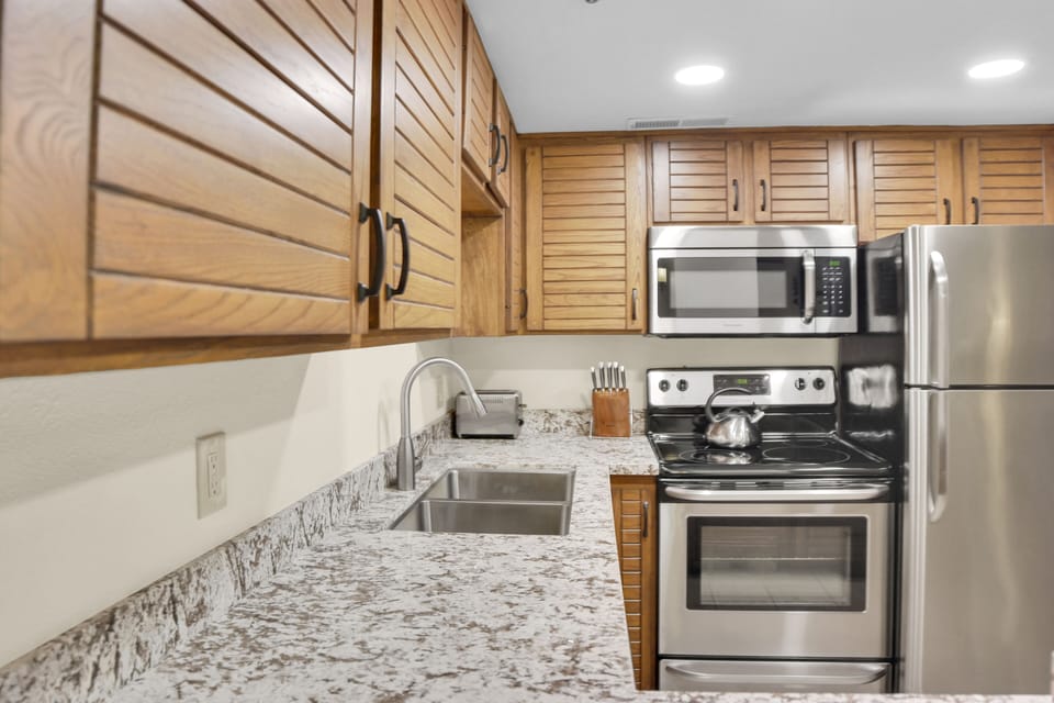 Park Station 214's kitchen offers stainless steel appliances, wood cabinets, and grey and white counter tops.
