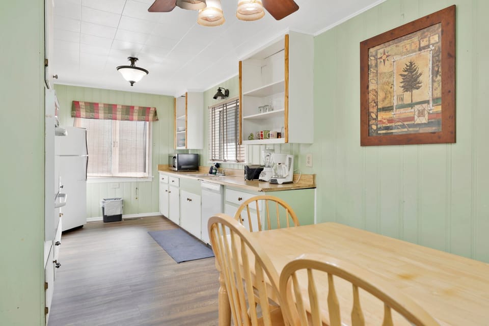 Kitchen with a refrigerator, stove, microwave, oven, toaster, coffee machine, blender, dishwasher, and a dining table to enjoy a delicious meal.