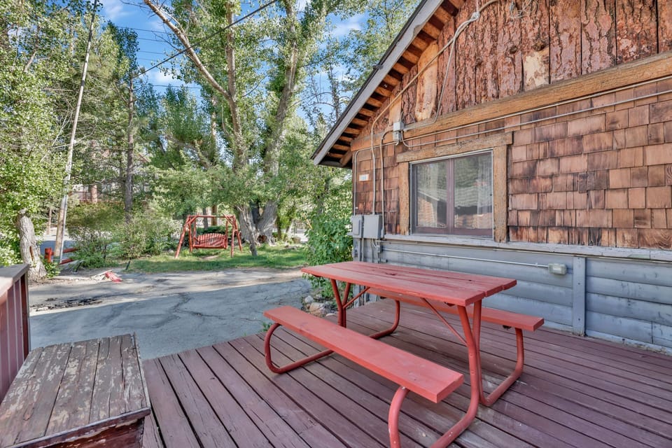 Enjoy outdoor dining on a private cabin deck with picnic table, surrounded by trees and fresh mountain air—perfect for morning coffee, BBQs, and relaxing nature-filled getaways.