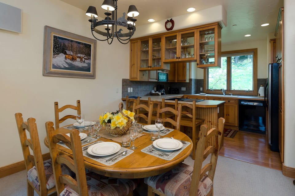 Gather around your warm wood dining table, perfectly set for memorable meals with loved ones in this inviting kitchen space.