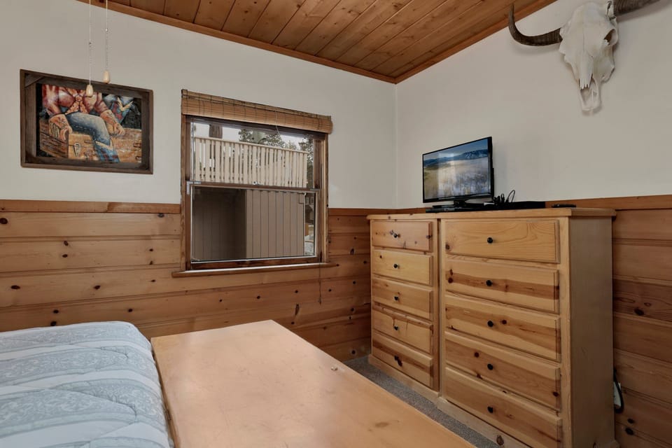 Peaceful cabin bedroom with plush bedding, vaulted wood ceilings, and forest views—ideal for restful nights, cozy mornings, and a relaxing mountain escape.