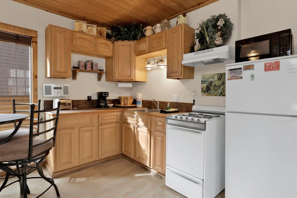 Fully equipped cabin kitchen with warm wood cabinets, gas stove, fridge, microwave, and coffee maker—perfect for cooking meals, morning coffee, and feeling right at home on your Airbnb stay.