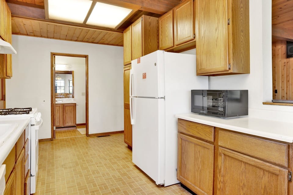 Fully equipped cabin kitchen with warm wood cabinets,stove, fridge, microwave, and coffee maker—perfect for cooking meals, morning coffee, and feeling right at home on your stay.