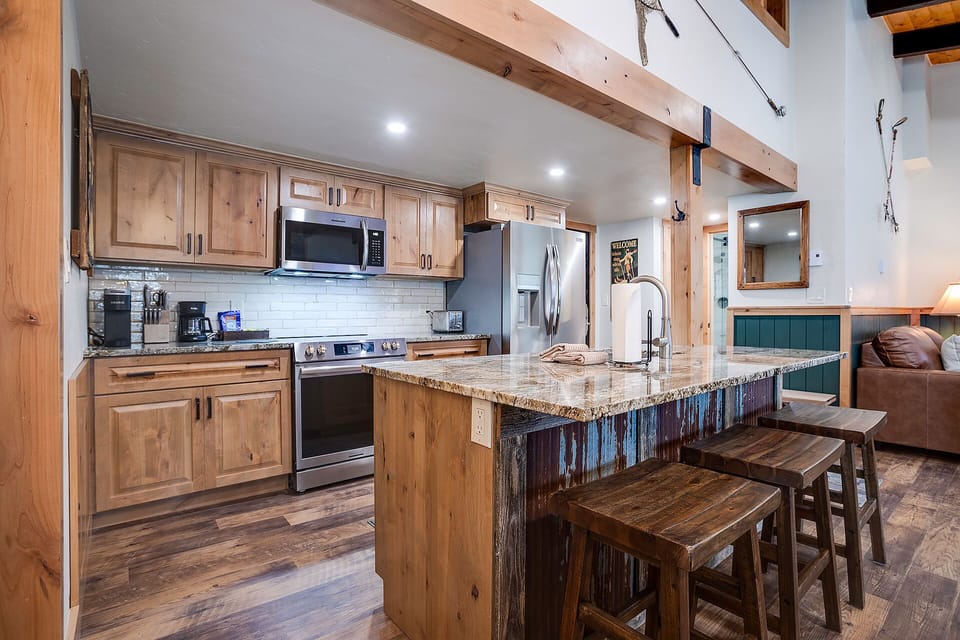 Your rustic kitchen features warm wood cabinets, granite countertops, and exposed beams creating a cozy mountain retreat atmosphere.