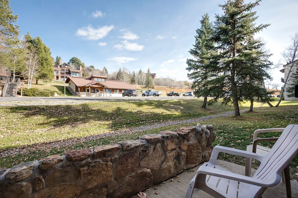 Scenic mountain property with parking and natural landscaping set among towering evergreens and rolling hills.