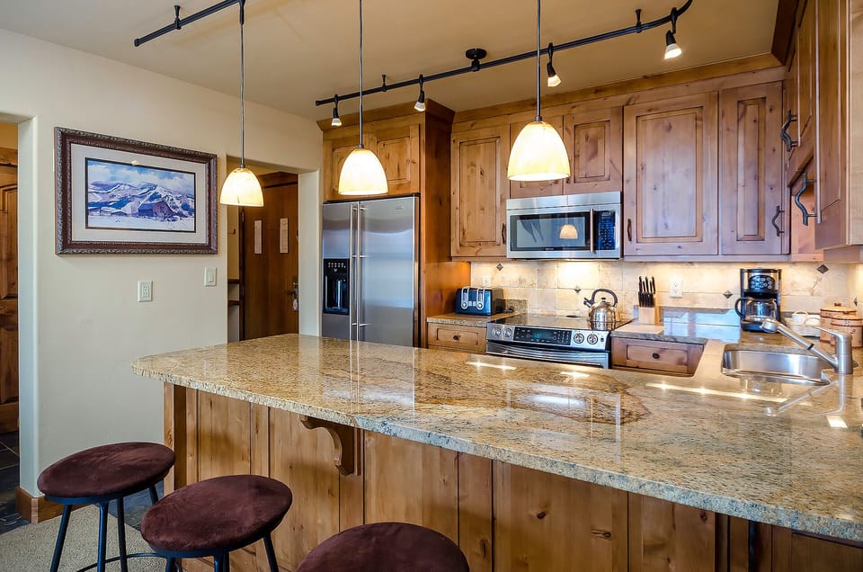 Discover your mountain retreat's gourmet kitchen, where granite countertops and warm wood cabinets create the perfect space for your culinary adventures.