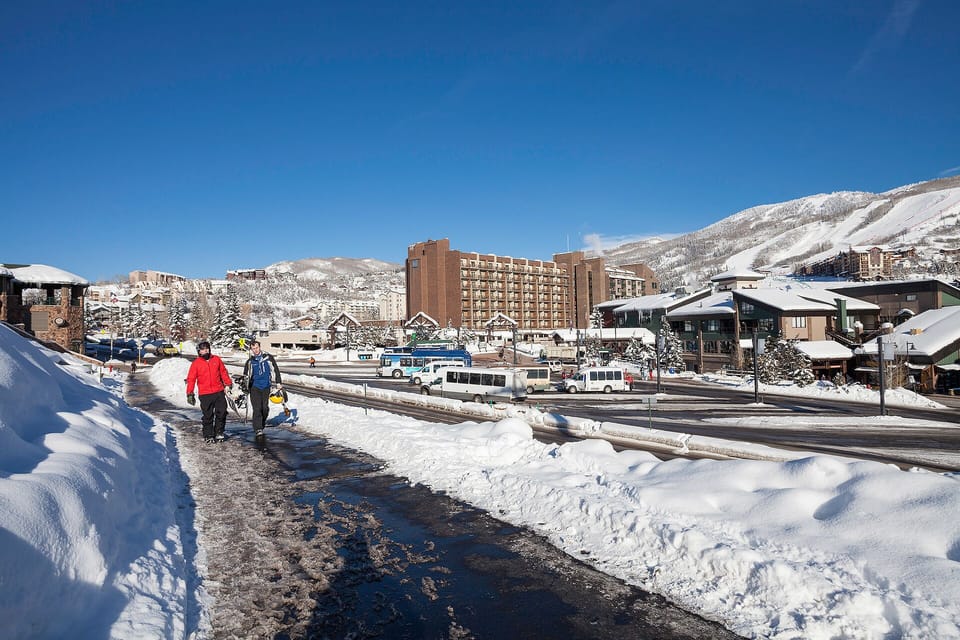 Winter resort village with snowy mountains, hotels, and convenient transit access for mountain adventures.