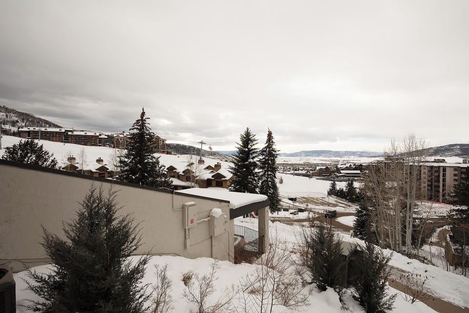 Snow-covered mountain resort town with ski slopes and alpine buildings nestled in the valley below.