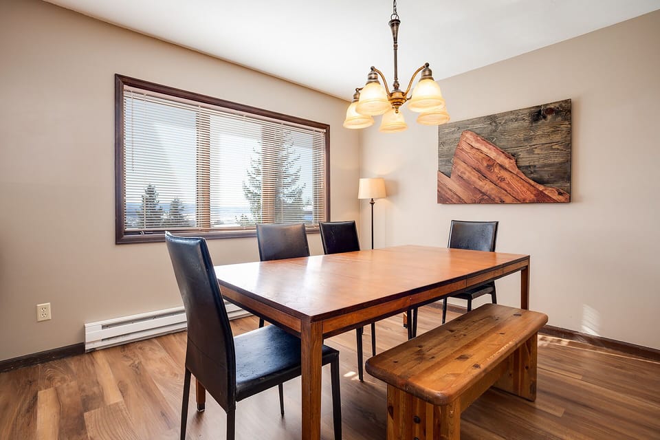 Gather around your elegant dining table for memorable meals, surrounded by warm wood tones and mountain-inspired artwork.