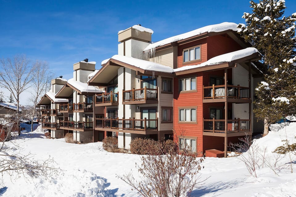 Modern mountain property featuring warm wood and stone architecture nestled in pristine winter landscape with snow-covered surroundings.
