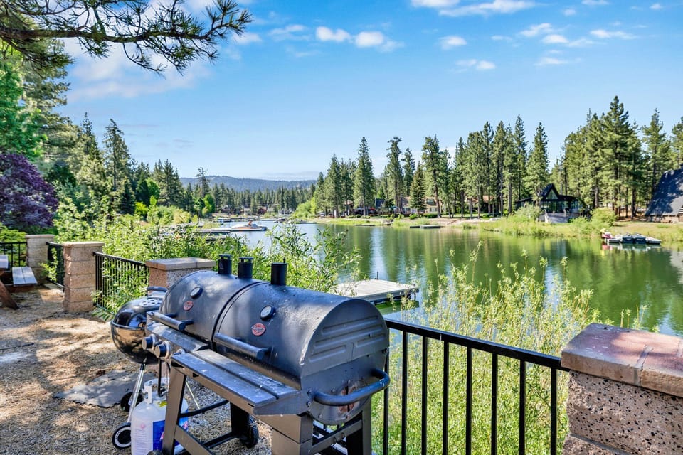 Scenic lakeside outdoor area with BBQ grills, picnic tables, and stunning water views—perfect for cookouts, relaxing afternoons, and unforgettable stays surrounded by nature.