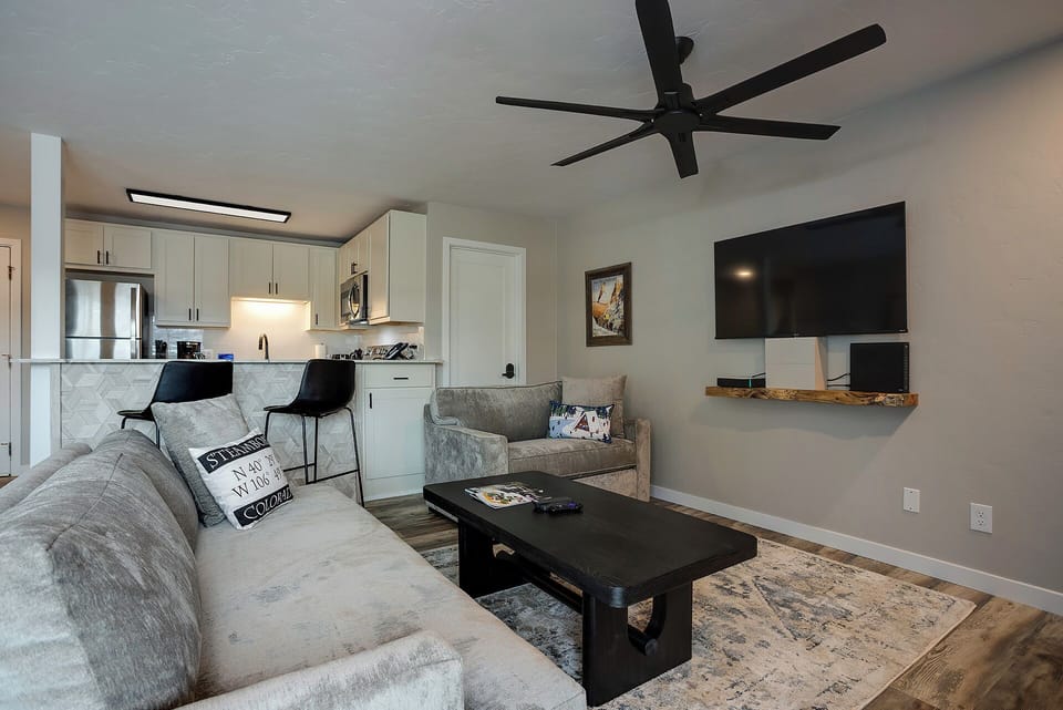 Relax in your stylish open-concept space where modern comfort meets thoughtful design, featuring plush seating and a fully-equipped kitchen.