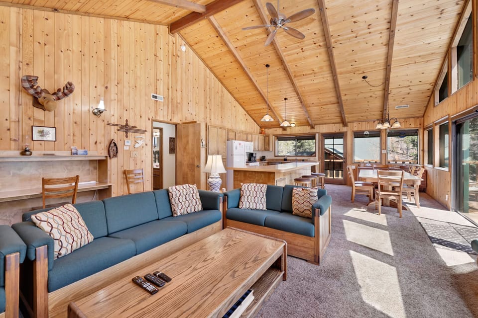 Stunning open-concept cabin with soaring wood ceilings, panoramic forest views, cozy fireplace, and spacious living area—perfect for group gatherings, relaxing escapes, and unforgettable mountain stays.
