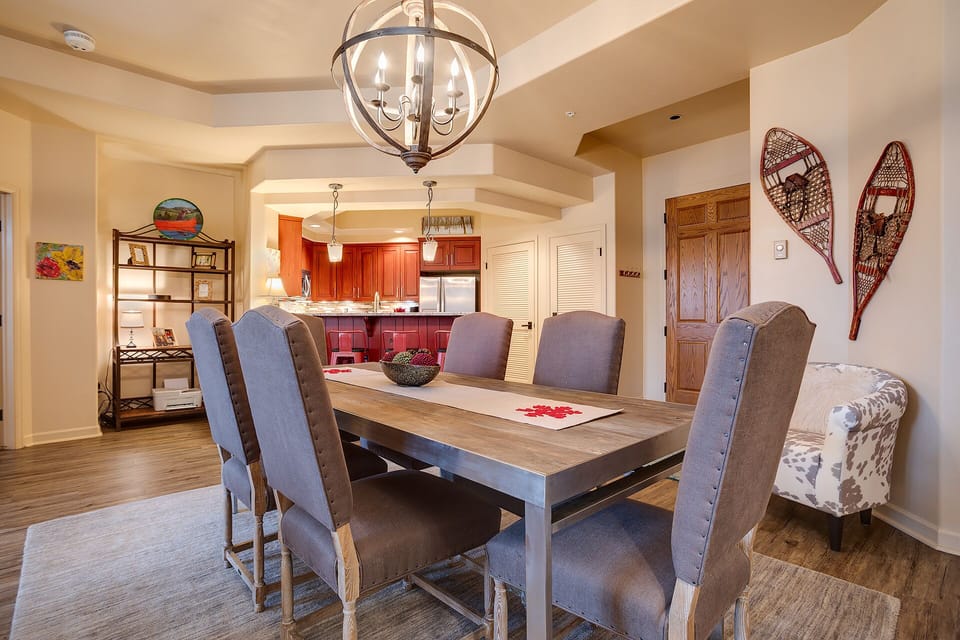 Gather around your elegant dining table where rustic snowshoes and warm lighting create the perfect mountain retreat atmosphere.