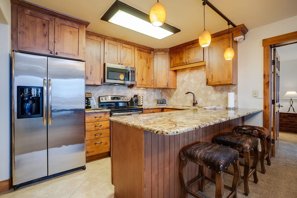 Cook your favorite meals in this fully-equipped kitchen featuring granite countertops, stainless steel appliances, and a convenient breakfast bar.