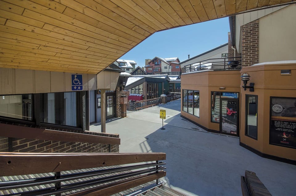 Modern shopping plaza with covered walkways leads to nearby mountain village amenities and services.