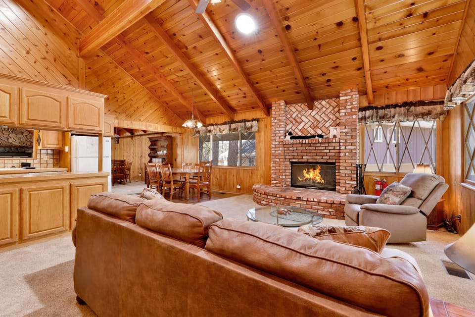 Cozy mountain living room with wood ceilings, stone fireplace, comfy seating, and smart TV—perfect for relaxing evenings, movie nights, and warm cabin vibes after outdoor adventures.