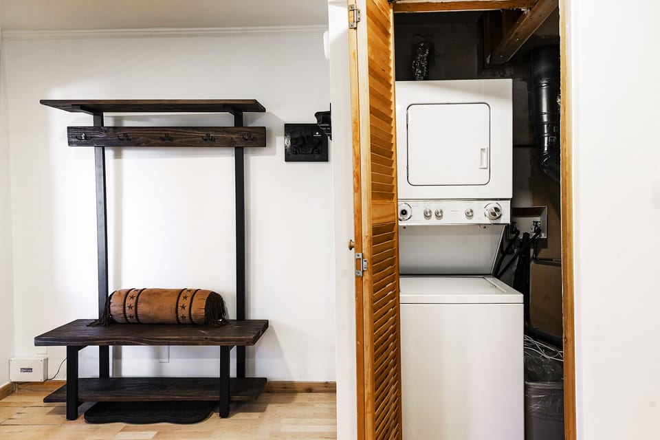 Entryway with convenient wooden bench and equipment rack and stacked washer/dryer