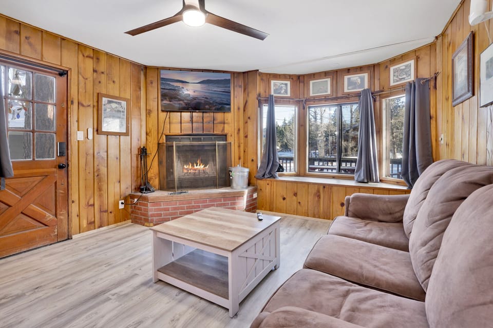 Cozy cabin living room with a stone fireplace, comfy seating, and rustic wood details—perfect for relaxing evenings, movie nights, and unforgettable mountain getaways.
