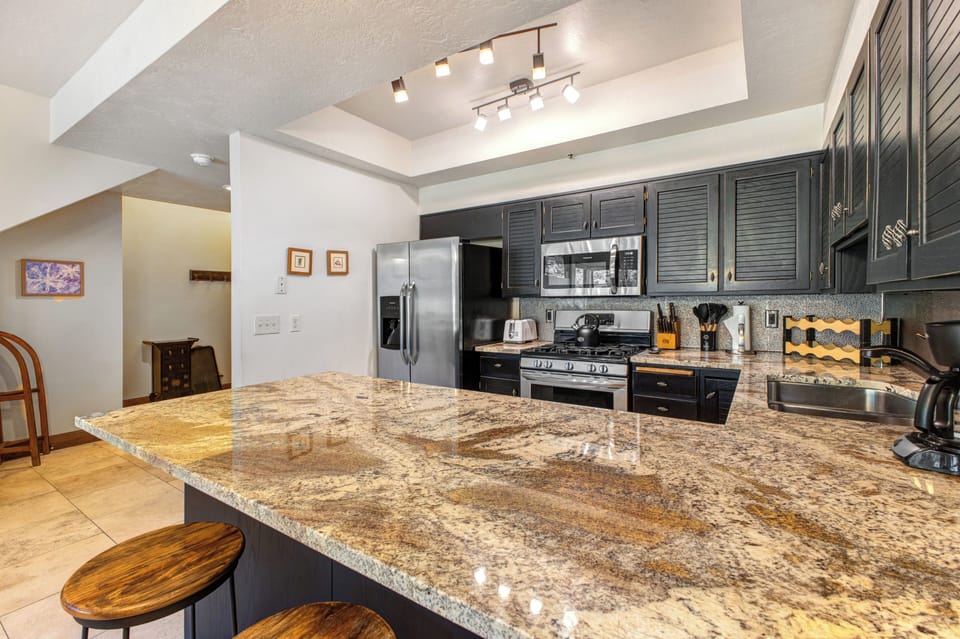 Queen Esther's kitchen has black painted wood cabinets, granite counters and stainless steel appliances.