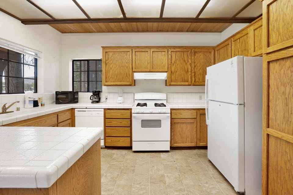 Fully equipped cabin kitchen with warm wood cabinets, stove, fridge, microwave, and coffee maker—perfect for cooking meals, morning coffee, and feeling right at home on your stay.
