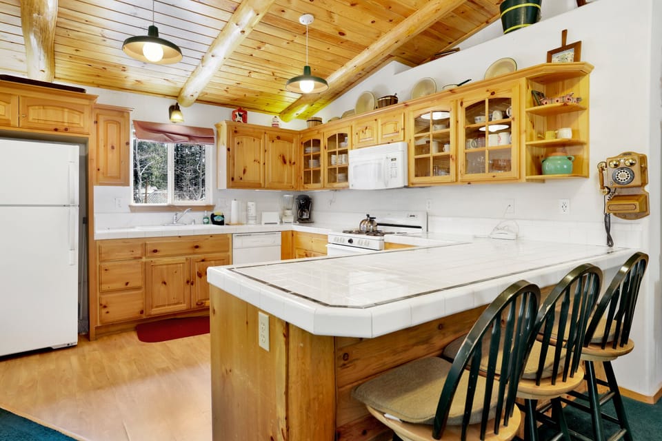 Kitchen with a refrigerator, stove, microwave, oven, toaster, coffee machine, blender, dishwasher, and a dining table to enjoy a delicious meal.