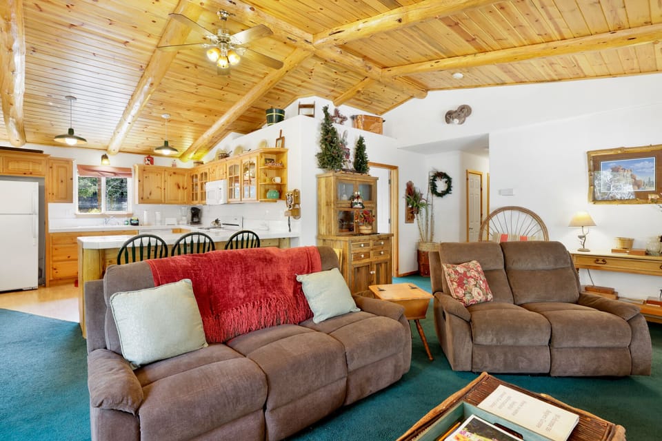 Cozy cabin living room with a stone fireplace, comfy seating, and a TV—perfect for relaxing evenings, movie nights, and unforgettable mountain getaways.