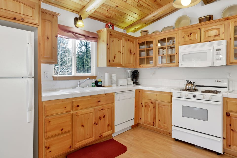 Kitchen with a refrigerator, stove, microwave, oven, toaster, coffee machine, blender, dishwasher, and a dining table to enjoy a delicious meal.
