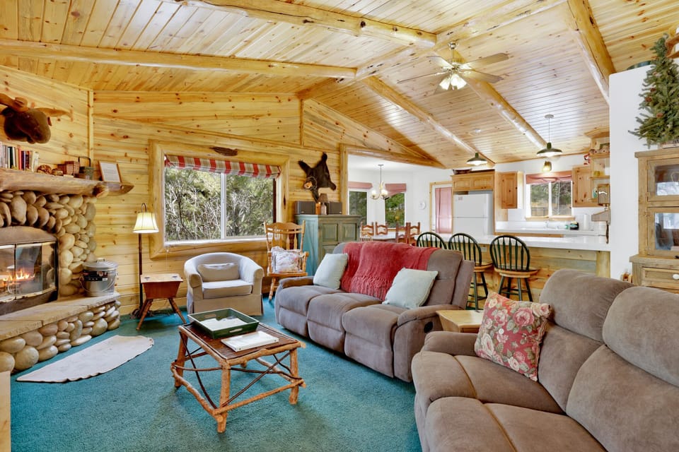 Cozy cabin living room with a stone fireplace, comfy seating, and a TV—perfect for relaxing evenings, movie nights, and unforgettable mountain getaways.