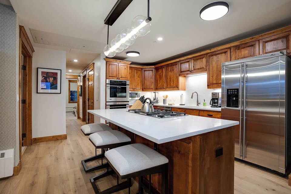 Your fully equipped gourmet kitchen features rich wood cabinetry, stainless steel appliances, and a spacious island perfect for cooking and gathering.